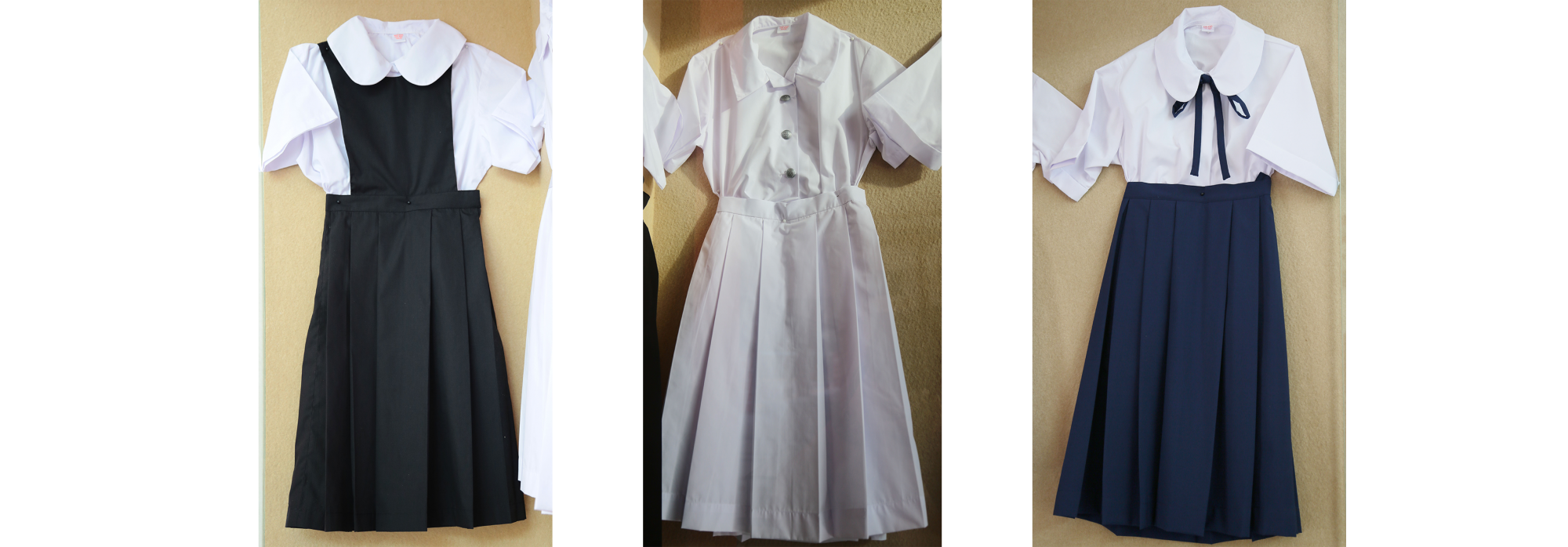 Three school uniform outfits: white blouse with black pinafore, all-white dress, and white blouse with navy pleated skirt.